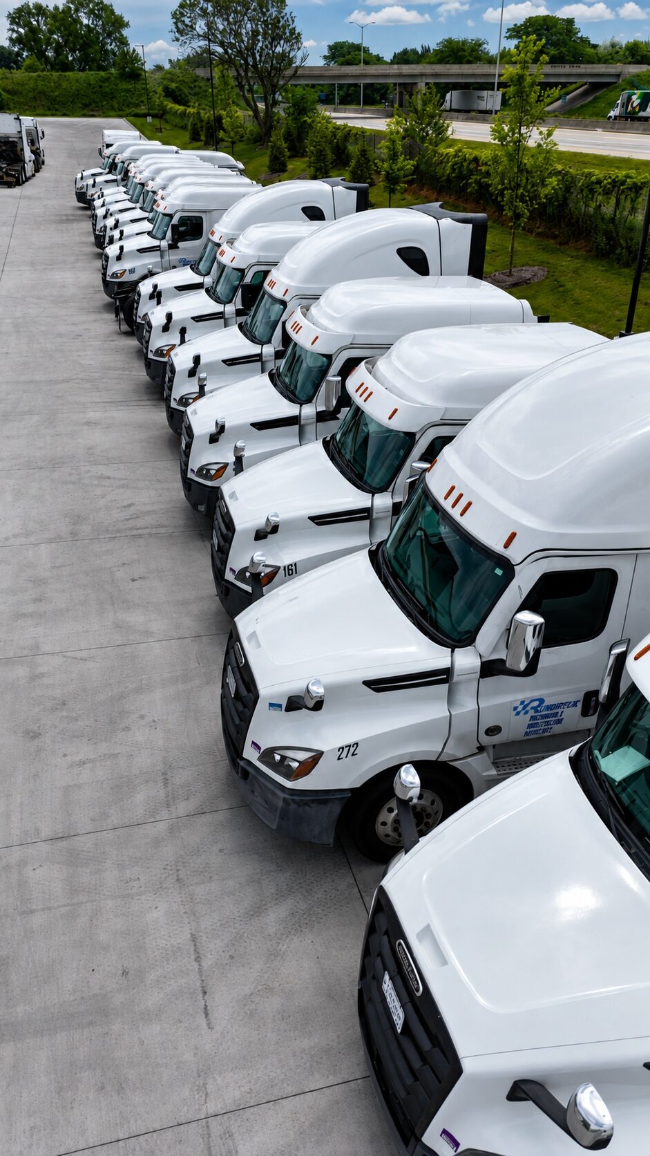 A row of Run Direct 2024 Freightliner Cascadia trucks parked in the yard